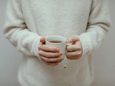 Relaxed hands holding a cup of tea near a window
